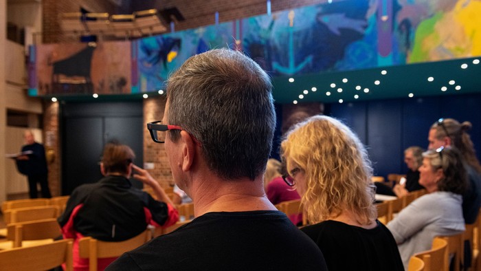 En gruppe af mennesker sidder i en kirke og ser op mod alteret.