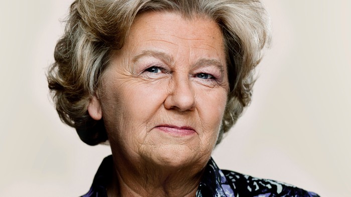 En eldre kvinde med kort, gråt hår og mørke, blå øjne.
