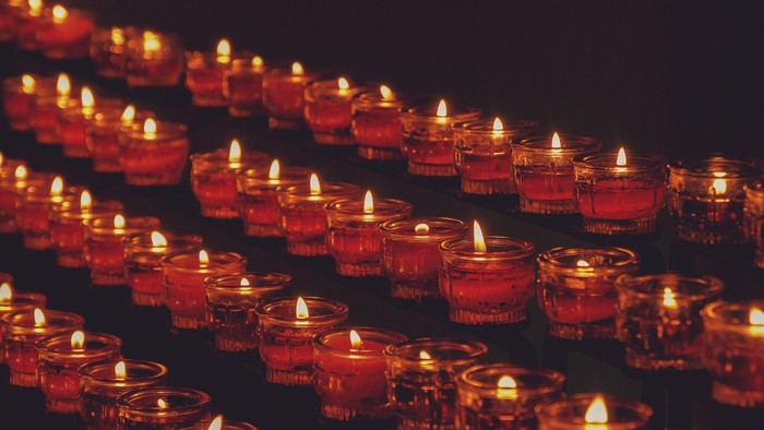 Viele brennende Kerzen in Glasgefäßen auf dunklem Hintergrund