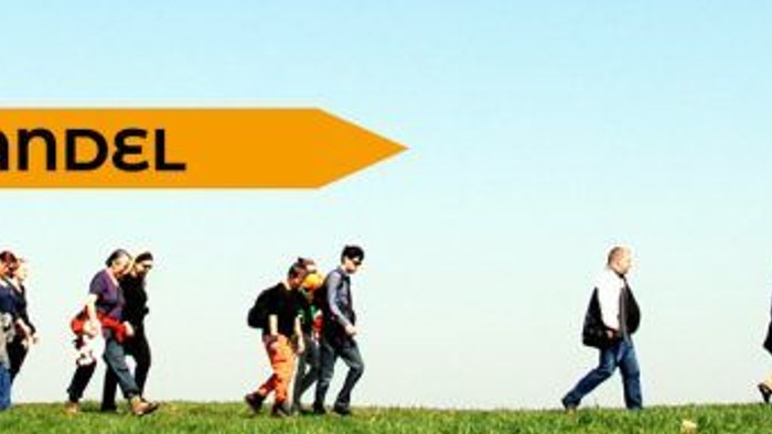 Foto: Viele Menschen wandern auf einer Wiese von links nach rechts. Darüber ist der Schriftzug "Kirche im Wandel" mit einem Pfeil nach rechts.