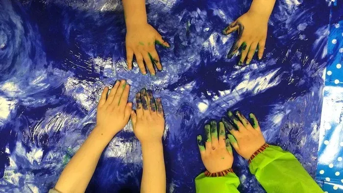 Kinderhände mit grüner Farbe auf blauem Hintergrund