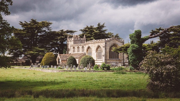 Large historic building with arched windows, surrounded by trees and a well-maintained lawn.