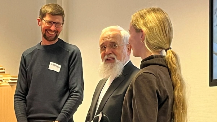 Drei Personen stehen und unterhalten sich freundlich