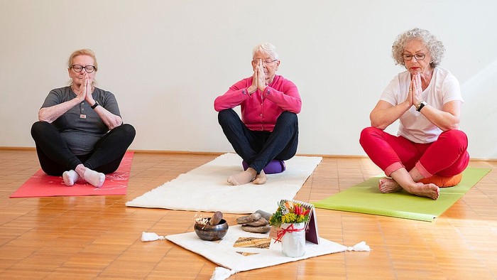 Drei ältere Frauen meditieren auf Yogamatten