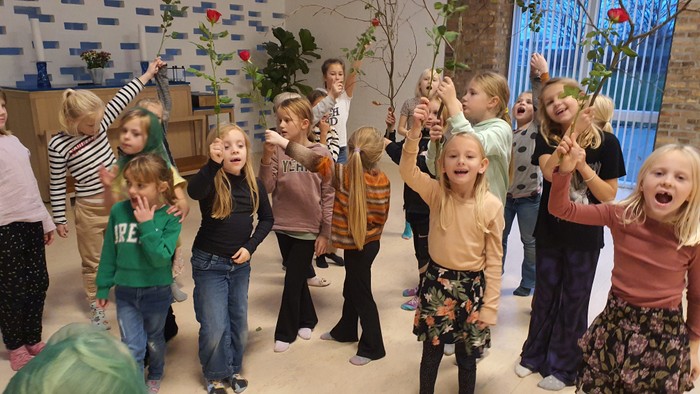 En gruppe børn danser og har sjov i et rum med blomster og dæk.