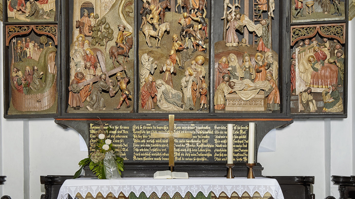 Das Bild zeigt einen verzierten Altar mit religiösen Darstellungen und Inschriften.