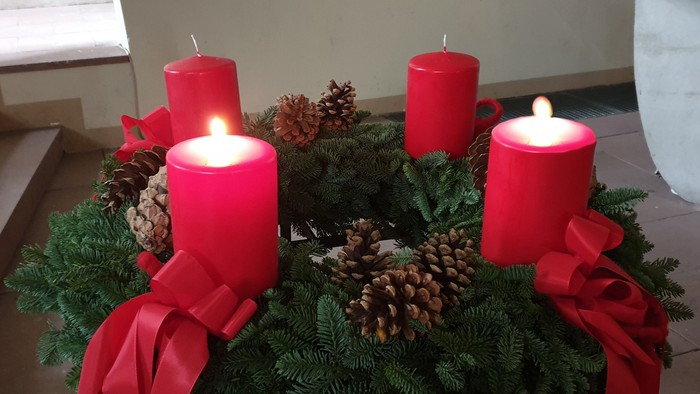 Weihnachtliche Dekoration mit vier roten Kerzen und Tannenzweigen