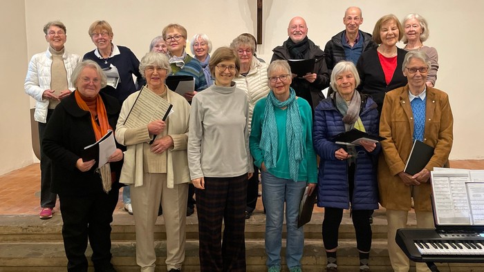 Gruppe von Erwachsenen, die drinnen in der Nähe eines Kirchenaltars posieren, mit Notenblättern und einem Keyboard.
