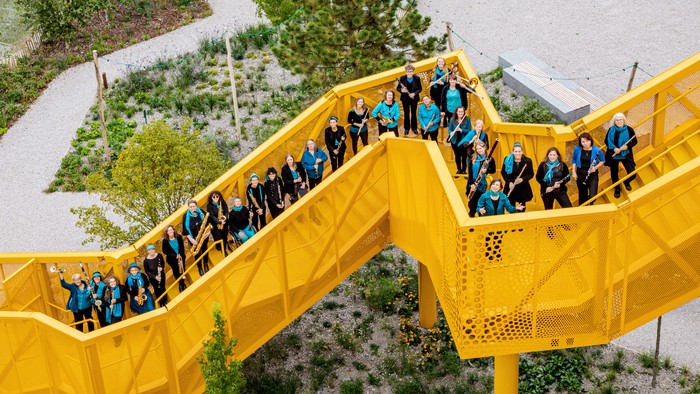 Eine Gruppe von Menschen steht auf einer gelben Brücke im Freien.