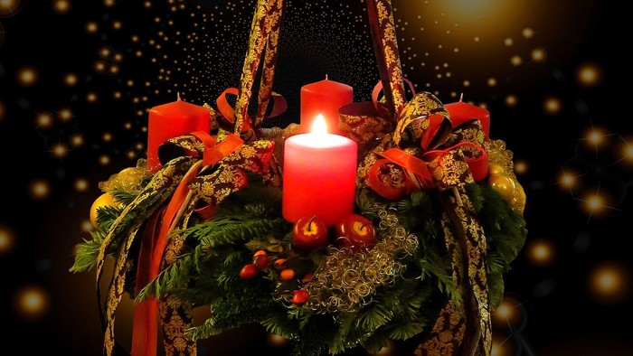 En hængende julelyst med grønne blomster og røde lys.