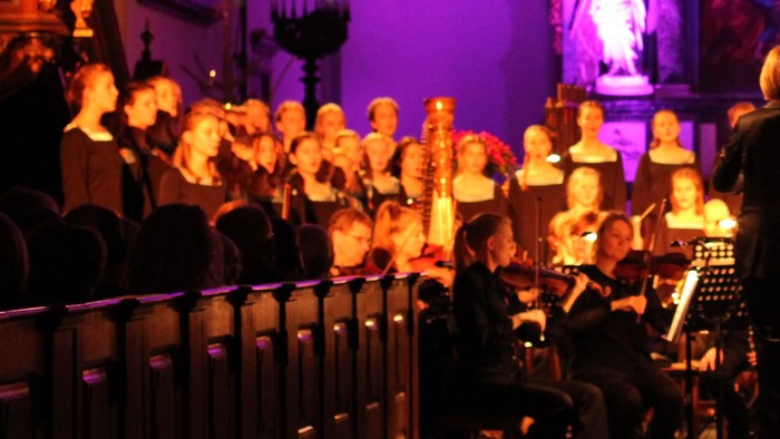 En kirke med en stor kor, der synger under lys fra kandle.
