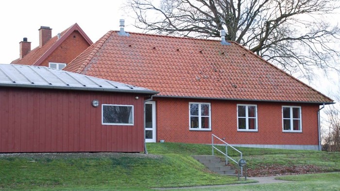 Rødt teglstenhus med rødt tag og trappe op til indgang