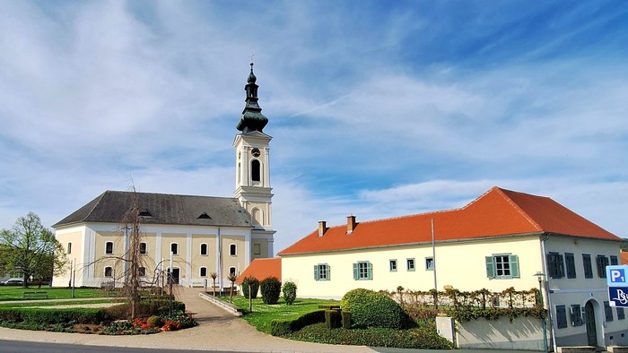Weißes Gebäude mit hohem Turm und rotem Dach unter blauem Himmel