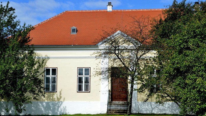Ein weißes Haus mit rotem Dach und grünem Rasen vor einem klaren blauen Himmel.