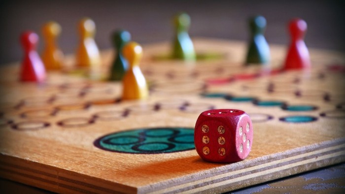 Holzspielbrett mit bunten Spielfiguren und Würfel