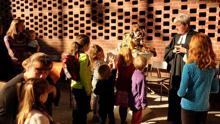 Kinder und Erwachsene vor Ziegelmauer