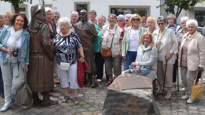 Eine Gruppe älterer Menschen posiert vor einer Statue