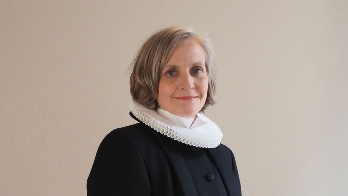 Kvinde i sort kaptajnmø, hvid krage og hvid kuffe.