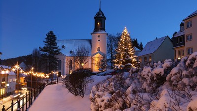 Weihnachtliche Dorfkulisse mit beleuchteter Kirche und Christbaum