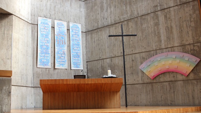 Die Kirche hat einen modernen Altar und ein farbiges Fenster.