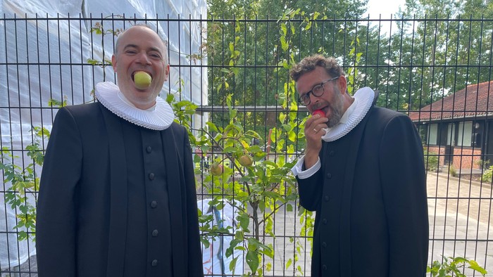 To nuns spiser æbler ved en hegn.