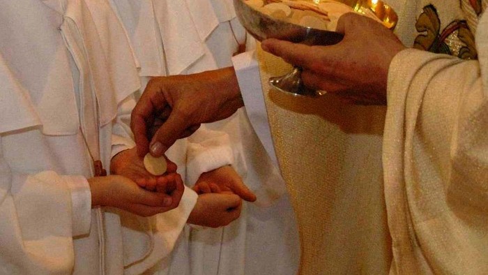 Personen in weißen Gewändern halten eine Schale mit Gegenständen