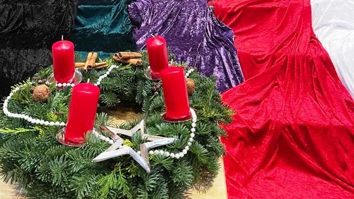 Weihnachtsdekoration mit Kerzen und Tannenzweigen auf rotem Stoff