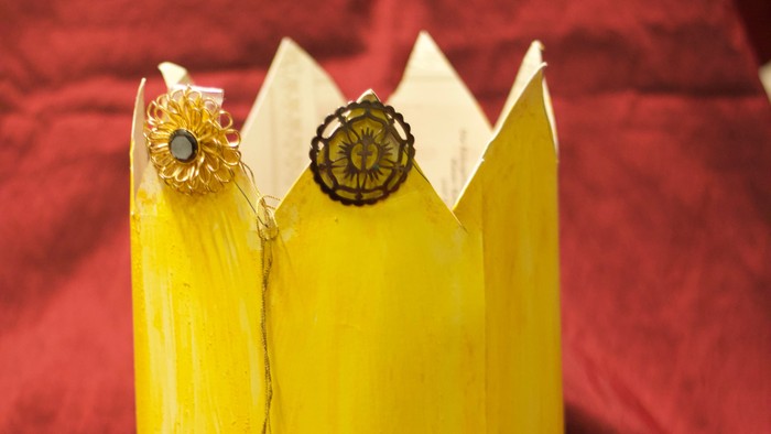 Gelbe Krone mit Edelsteinen auf rotem Stoff