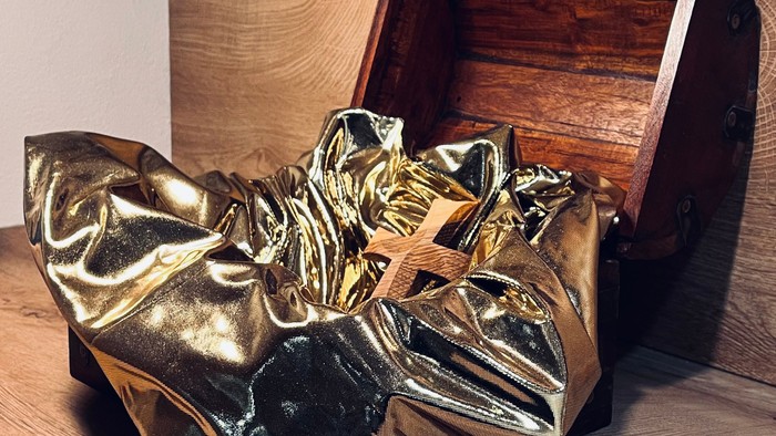 Goldene Stiefel vor einer Holztruhe