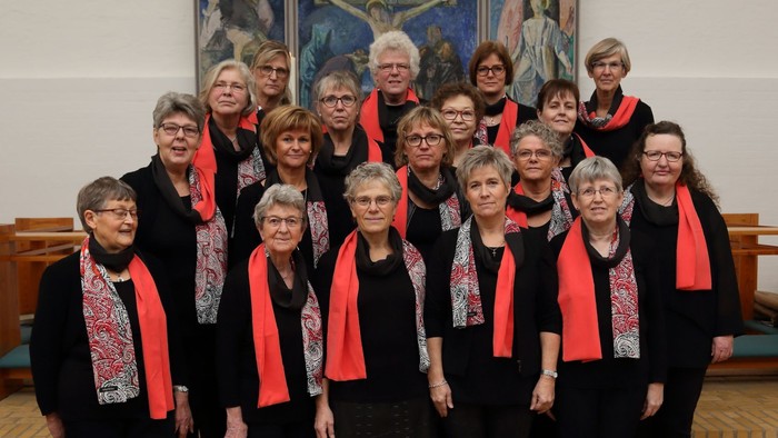 En gruppe kvinder i svart og rødt stander sammen i en kirke.