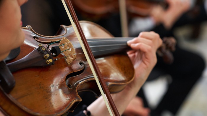 Eine Person, die Geige spielt und sich auf das Instrument und die Hände konzentriert