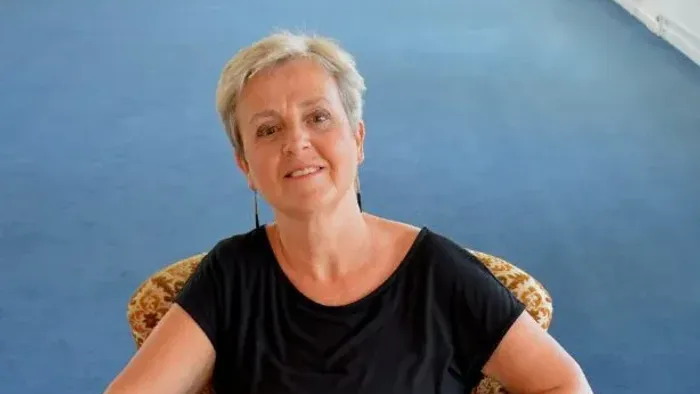 En person sidder behageligt i en prægtig lænestol med bare fødder og smiler varmt.