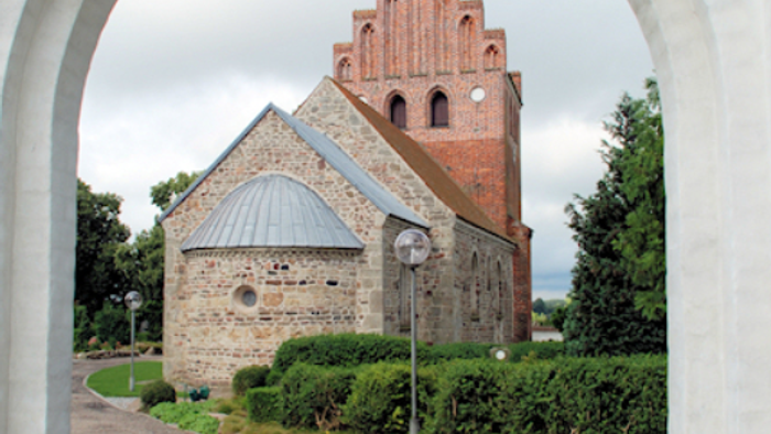 Bygning med spids tak og murstensvæg.