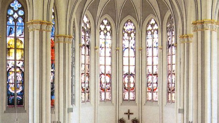 Innenraum einer Kirche mit hohen Säulen und buntem Glasfenster