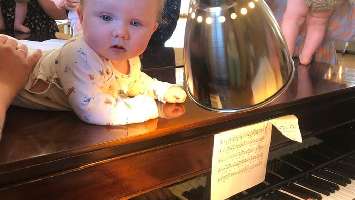 Børn ser i spejl mens en voksende spiller piano