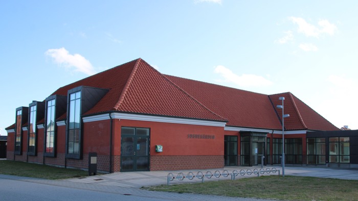 Et rødt teglsteinsgavl med store vinduer og en indgang med en rød tak.