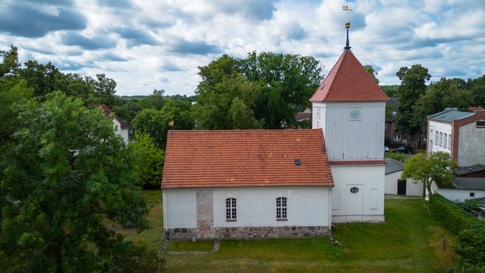 Weißes Gebäude mit rotem Dach und Turm in ländlicher Umgebung
