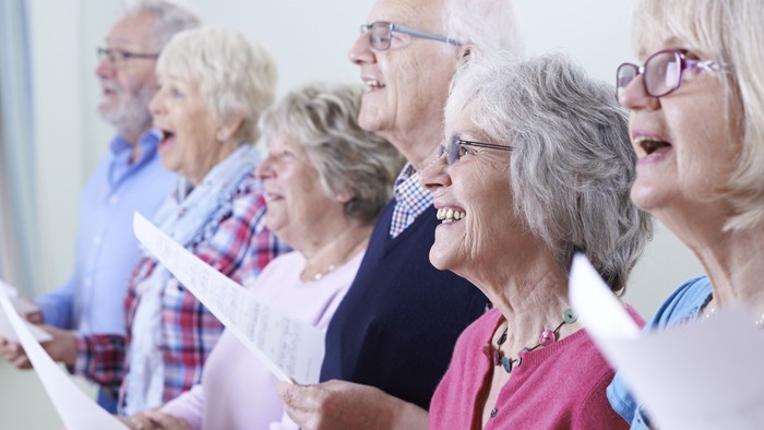 En gruppe ældre mennesker, der synger sammen og holder nodeark.