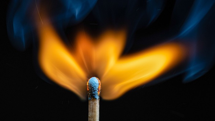 En tændstik brænder med blå og gule flammer.
