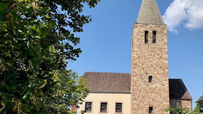 Kirche mit hohem Turm und daneben geparktem Auto.