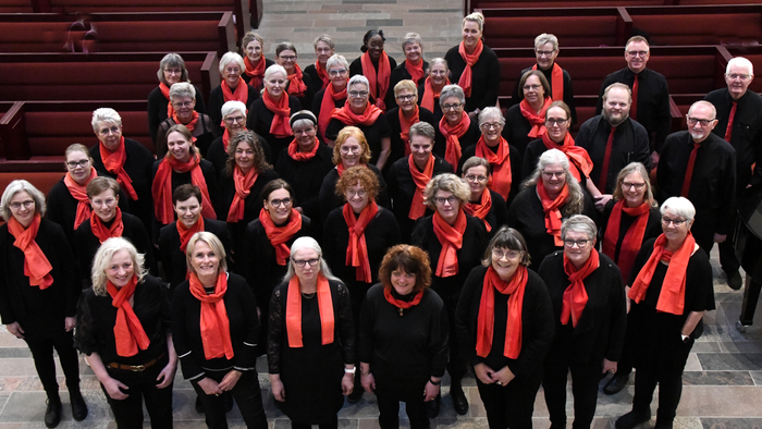 Gruppe af mennesker med røde halstørklæder og sort påklædning, der poser sammen.