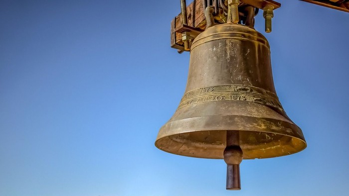 Ein großer, goldfarbener Glockenturm vor blauem Himmel