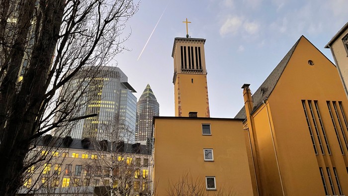 Altes Kirchengebäude vor moderner Stadtlandschaft