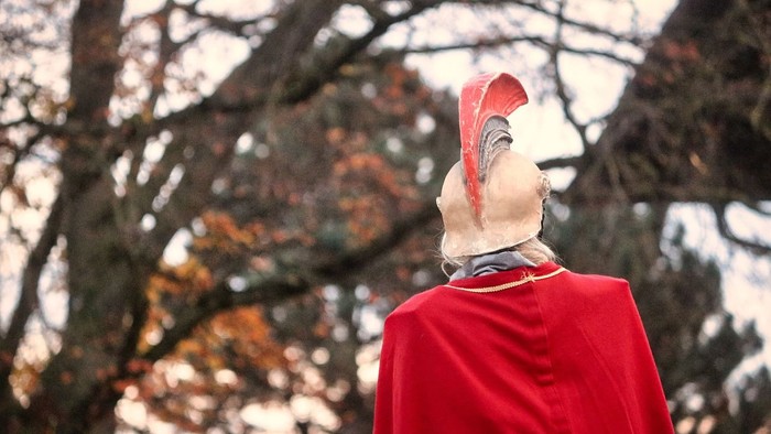 Person in rotem Umhang steht vor Baum