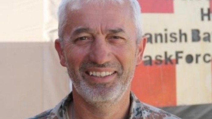 Foto af Frank Lissner i soldateruniform med dannebrog i baggrunden 