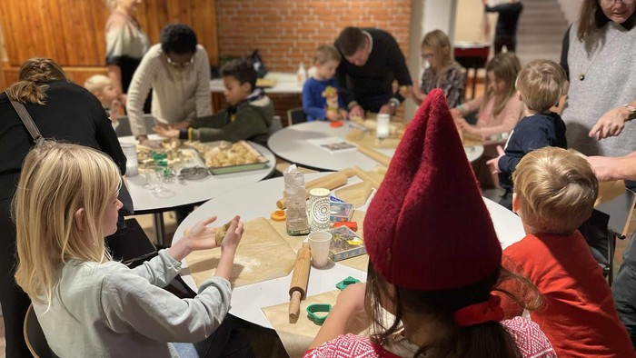 Familiesamling omkring bordet med mad og børn, der leger.