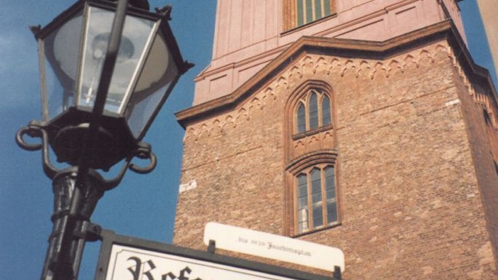 Lampenpfahl und Reformationsplatz-Schild vor Ziegelgebäude