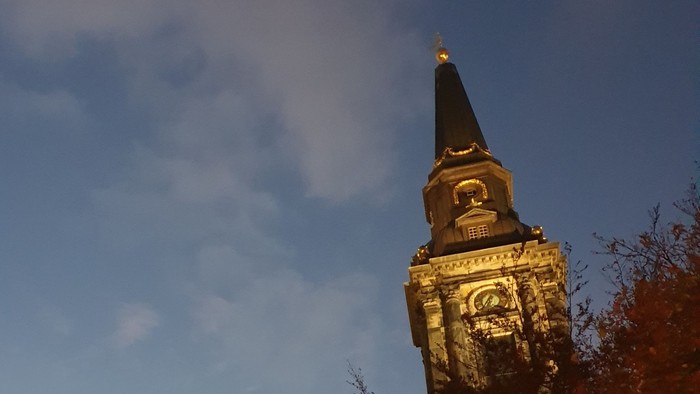 En belyset kirke med tårn mod en blå himmel.