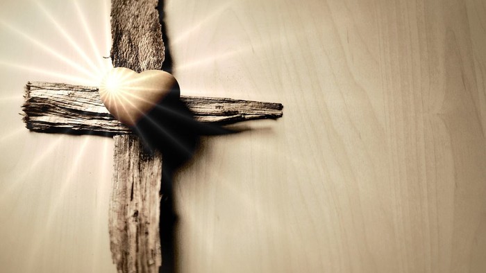Ein hölzernes Kreuz liegt auf einem Holzboden.