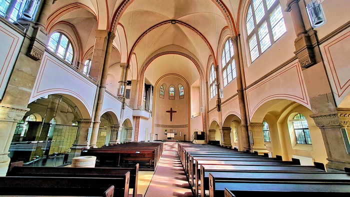 Innenraum einer Kirche mit hölzernen Kirchenbänken und hohen Bögen